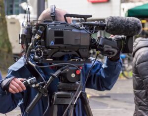 「報道用カメラを構えるテレビクルーの姿──メディアの情報発信とその背後の構造を象徴」