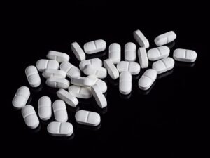 黒い背景の上に白い錠剤が多数散らばっている。対照的な色使いで薬の存在感が強調されている。